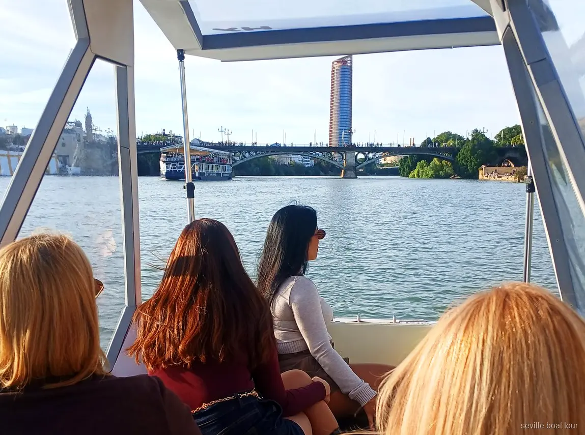 Passagères sous l'auvent d'une balade en bateau privée à Séville vers le pont de Triana et Torre Sevilla