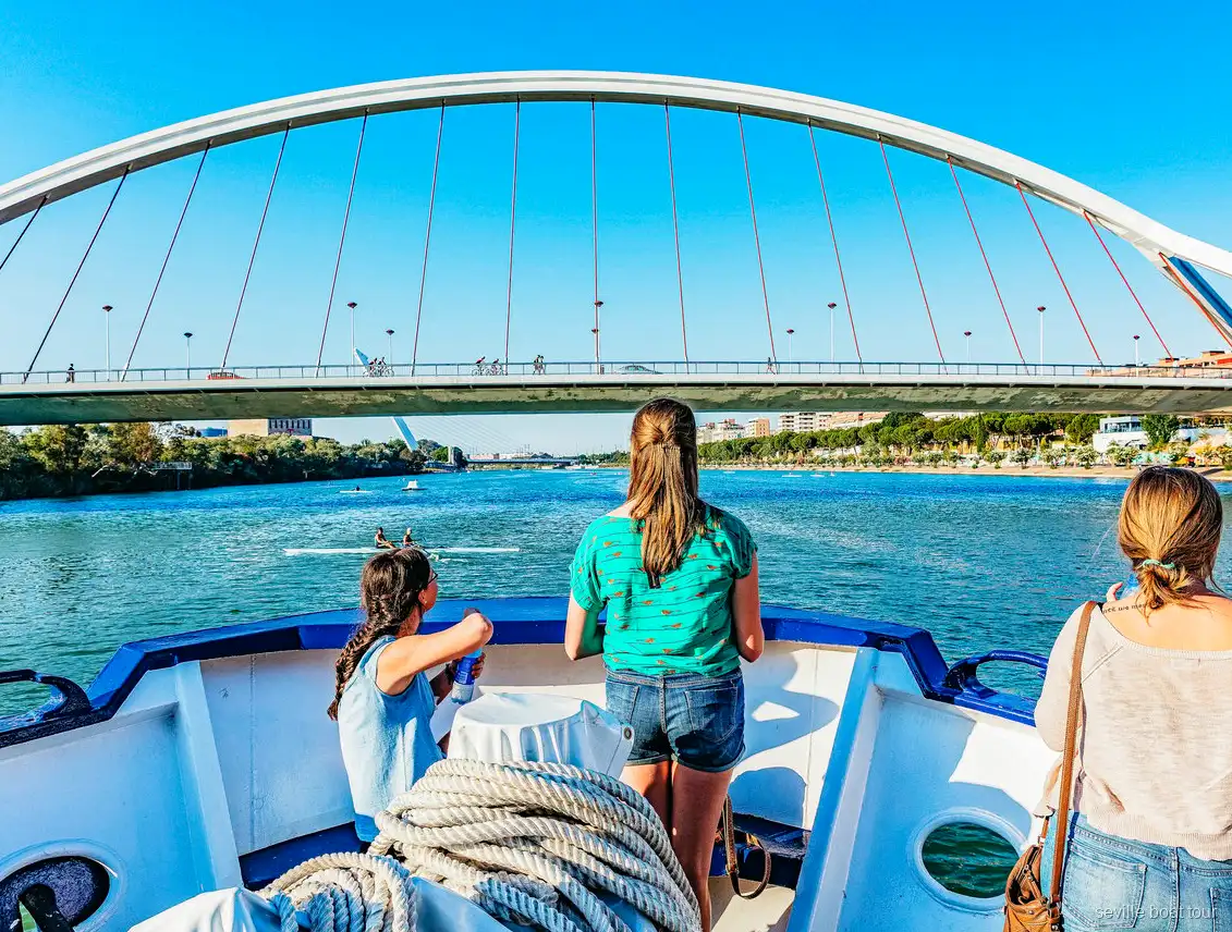 Passagers à la proue d'une balade en bateau à Séville en approche du pont de la Barqueta