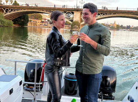 Coppia che brinda con champagne sul giro in barca romantico a Siviglia