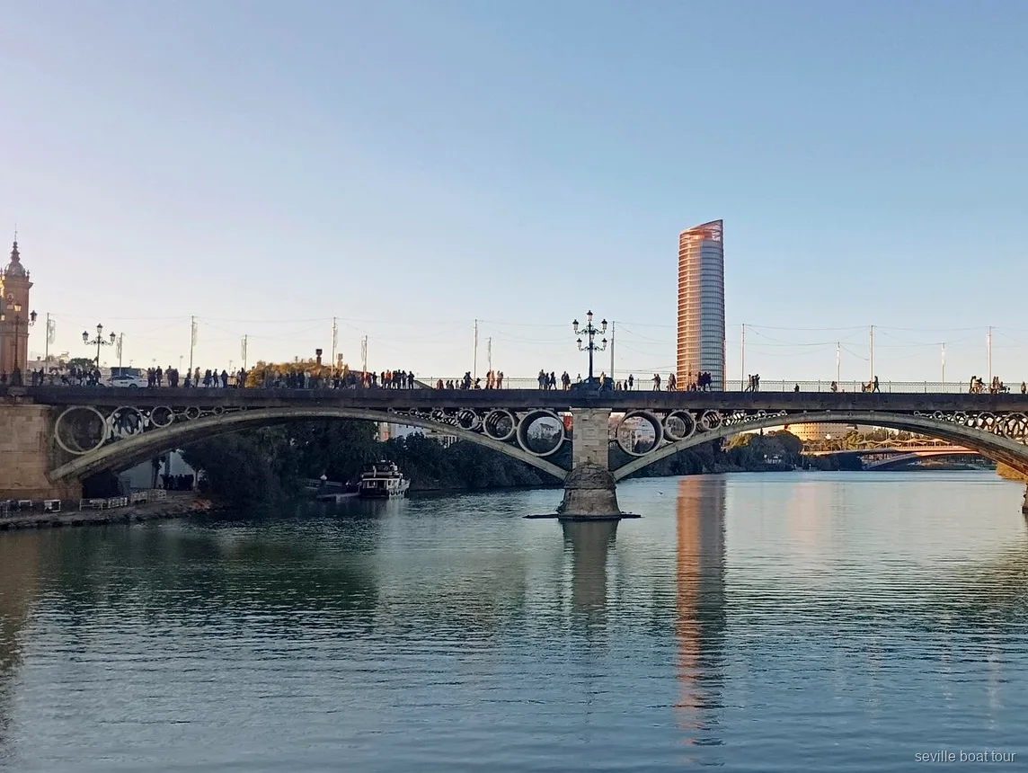 Triana Bridge and Torre Sevilla at golden hour seen on a Seville boat tour along the Guadalquivir